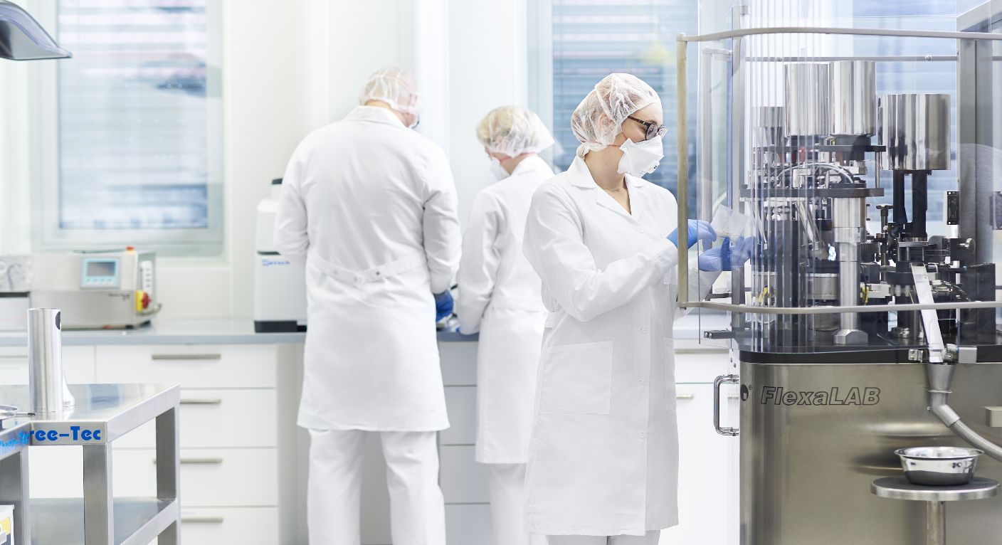Staff in lab coats working with lab equipment.